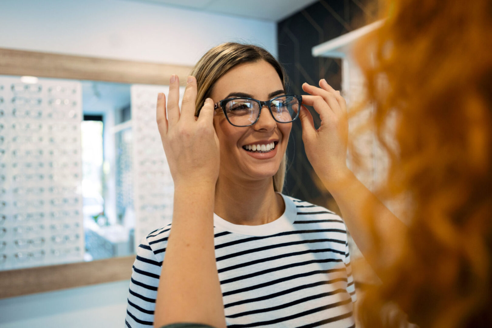 Woman trying on glasses at optician's.